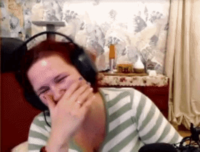 a woman wearing headphones is laughing while sitting in a room .