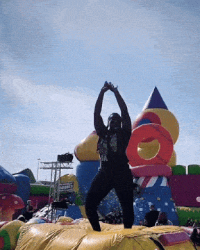 a man wearing a shirt that says ninja stands on a bouncy house