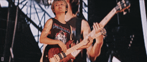 a man playing a guitar wearing a one ok rock shirt