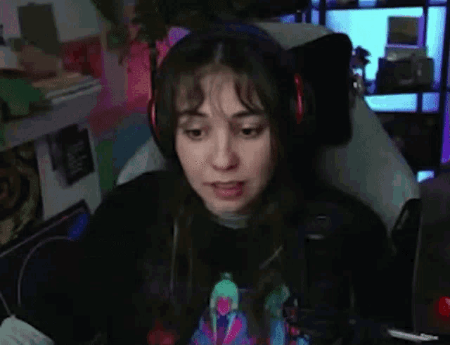 a woman wearing headphones and a black shirt is sitting in a chair in front of a computer screen .