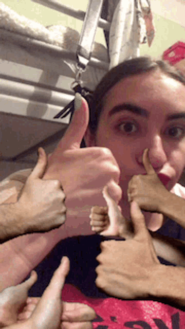 a woman is giving a thumbs up sign with many hands around her