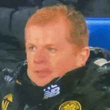 a man with red hair is wearing a black jacket with new balance written on it