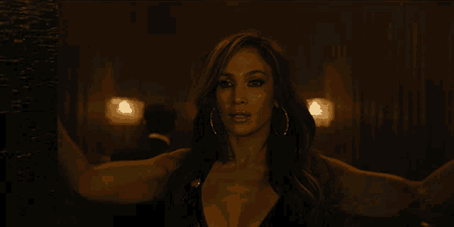 a woman is standing in a dark room with a candle in the background