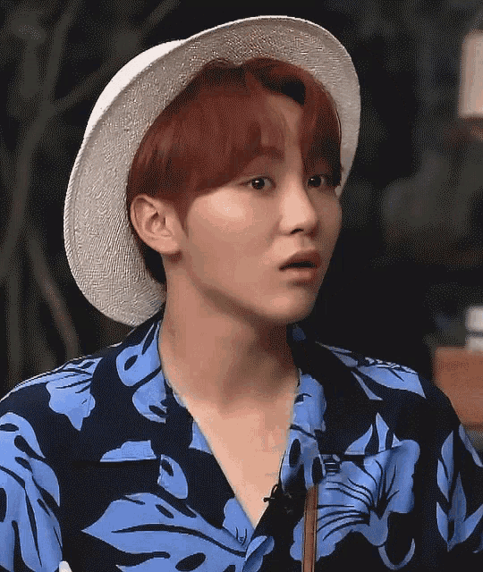 a man with red hair wearing a hat and a blue shirt with the word aloha on it