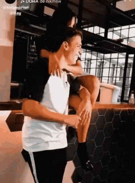 a man is carrying a woman on his shoulders while she sits on a counter .