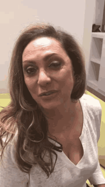 a woman wearing a white shirt with a plunging neckline is looking at the camera