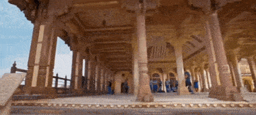 a group of people standing in a building with columns and arches