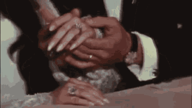 a bride and groom are putting their wedding rings on each other 's fingers .