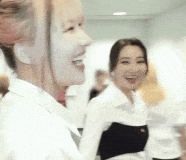 two women are smiling and laughing in a room while standing next to each other .