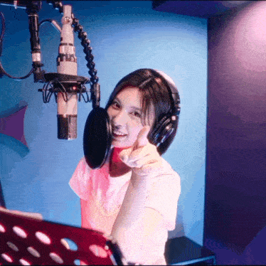 a woman giving a thumbs up while wearing headphones and a microphone