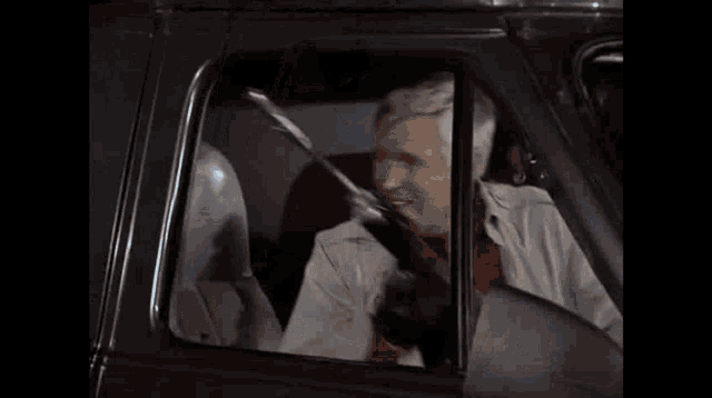 a man in a car is holding a gun in his hand .