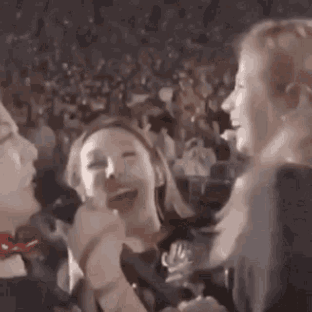 a group of women are standing next to each other in front of a crowd at a concert .