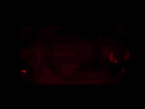 a blurry picture of a person in a dark room with a red light behind them