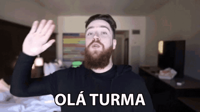 a man with a beard waves his hand in front of a sign that says olá turma
