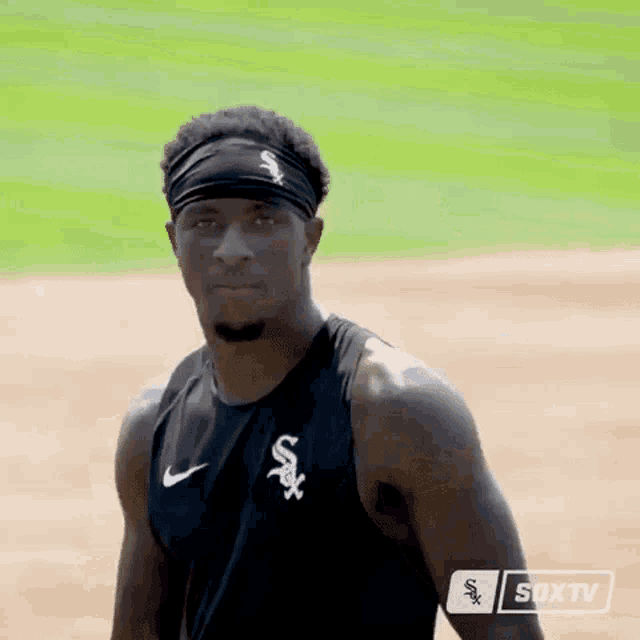a man wearing a black tank top with a white sox logo on the front