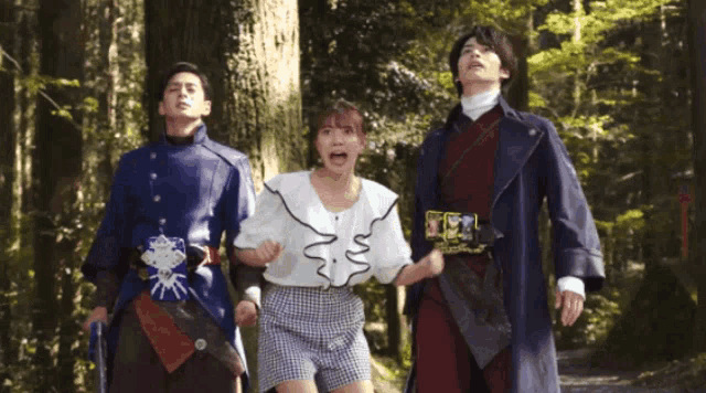 three people are standing in a forest and one of them is holding a sword .