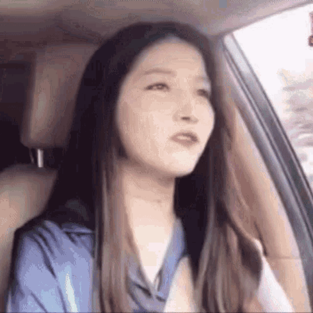 a woman is sitting in the driver 's seat of a car looking out the window .
