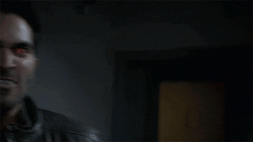 a man with red eyes and vampire teeth is making a funny face .