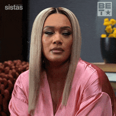 a woman in a pink robe is sitting in front of a sistas logo