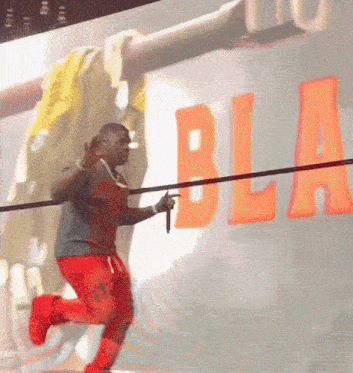 a man is holding a microphone in front of a wall that has the word bla on it