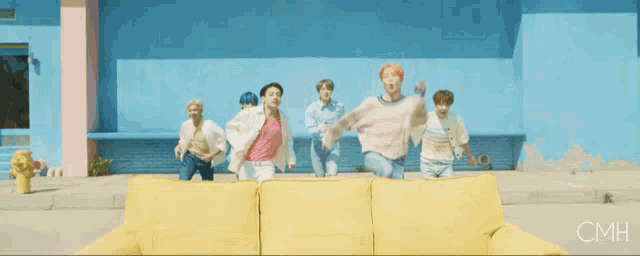 a group of young men are jumping on a yellow couch with cmh written on the bottom