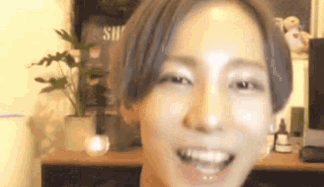 a close up of a person 's face with a plant in the background and a desk in the background .