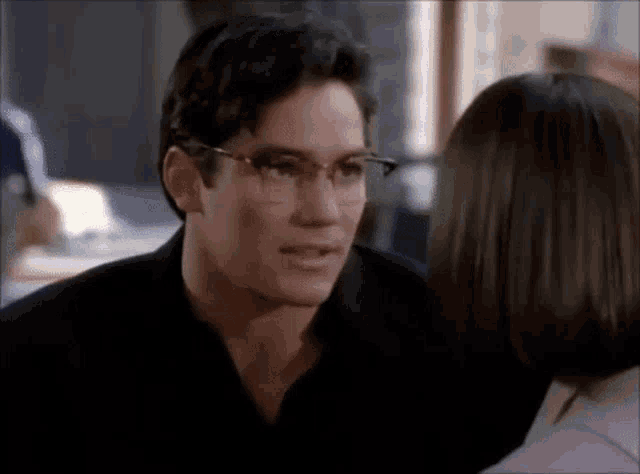 a man wearing glasses is talking to a woman .