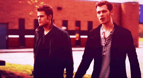 two men are holding hands and walking down a street