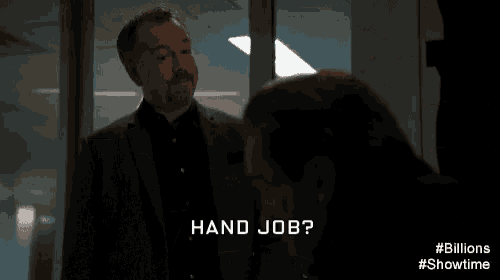 a man in a suit is giving a piece of paper to another man in a room .