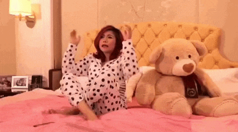 a woman in pajamas is sitting on a bed with a teddy bear .