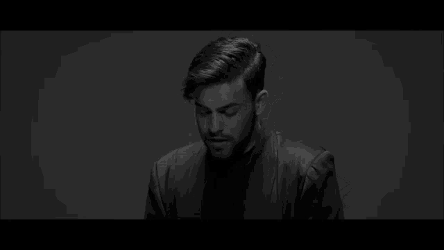 a black and white photo of a man with a beard and a leather jacket .