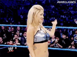 a woman in a wrestling ring giving a fist bump in front of a crowd