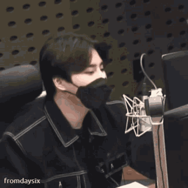 a man wearing a mask is sitting in front of a microphone in a radio station .