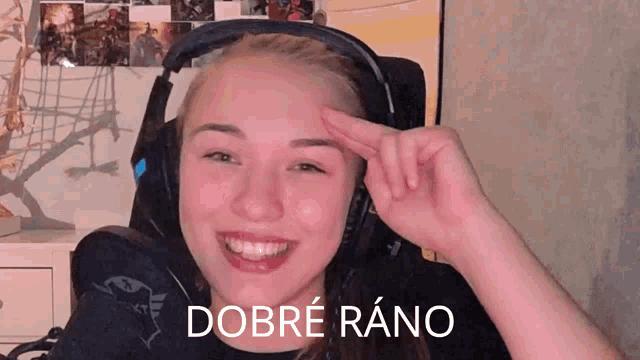 a woman wearing headphones is smiling and making a peace sign with her hand