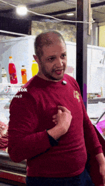 a man in a red shirt is standing in front of a display of bottles and says tiktok
