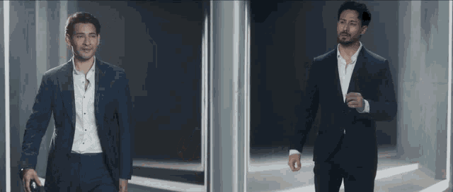 a man in a suit is standing next to another man in a suit