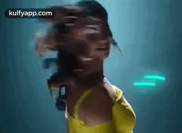 a blurry picture of a woman in a yellow dress dancing in a dark room .