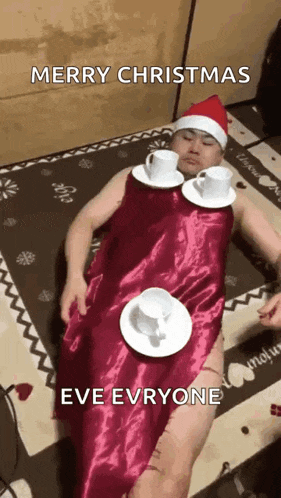 a man dressed as santa claus is laying on the floor with cups and saucers on his feet .