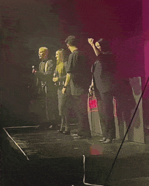 a group of people standing on a stage with microphones and a sign that says exit