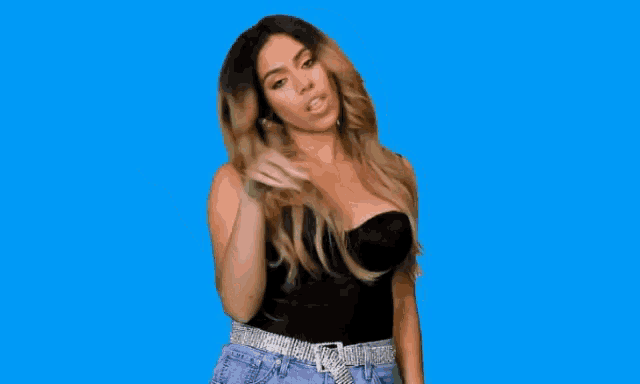 a woman in a black top and blue shorts is standing on a blue background .