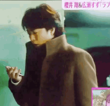 a man in a brown coat is holding a pen in his hand and looking at his phone .