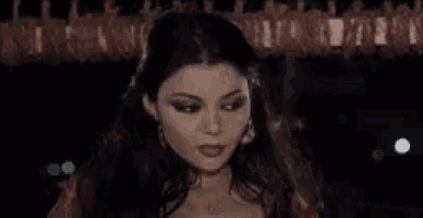 a woman is standing in a dark room holding her hair .