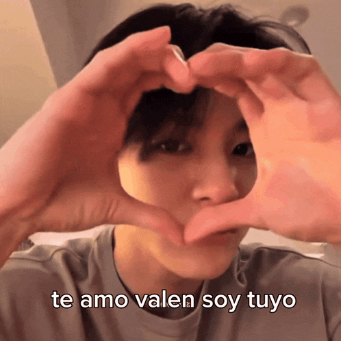 a person making a heart shape with their hands and the words te amo valen soy tuyo below them