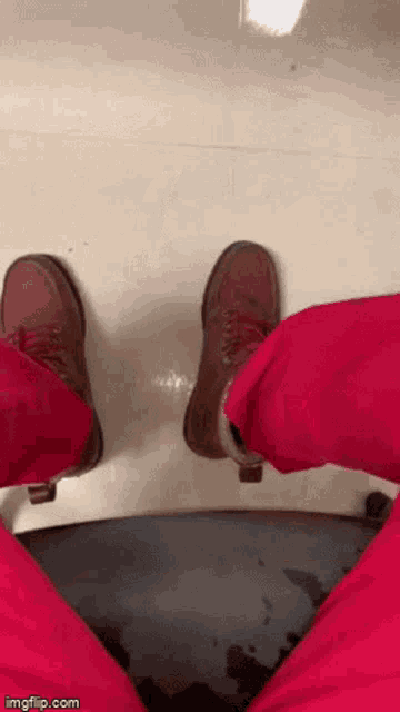 a person wearing pink pants and brown shoes is standing on a black surface ..