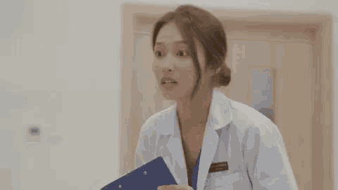a woman in a white coat is holding a clipboard and making a face .
