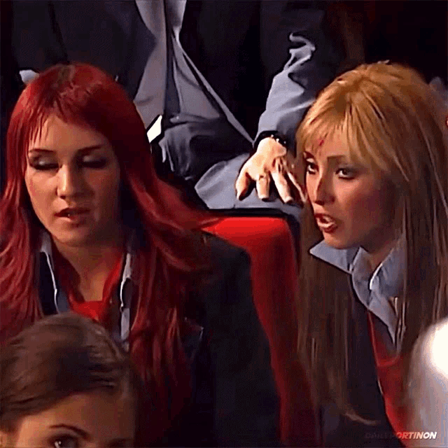 two women with red hair are sitting next to each other in a theatre .