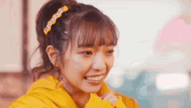 a girl wearing a yellow hoodie has a mustard hair clip on her head