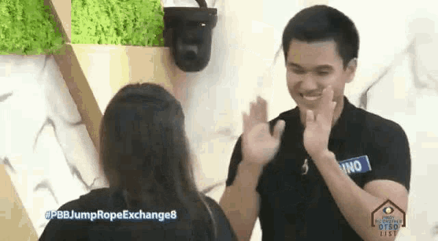 a man and a woman are giving each other a high five in front of a camera .