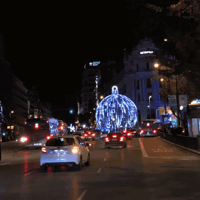 a busy city street at night with a building that says metropolitan on it