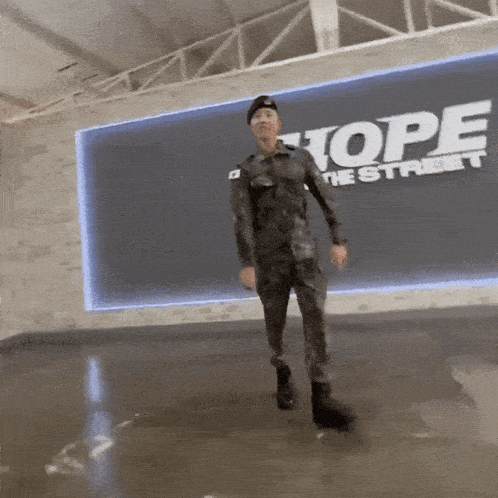 a man in a military uniform is dancing in front of a wall that says hope the street